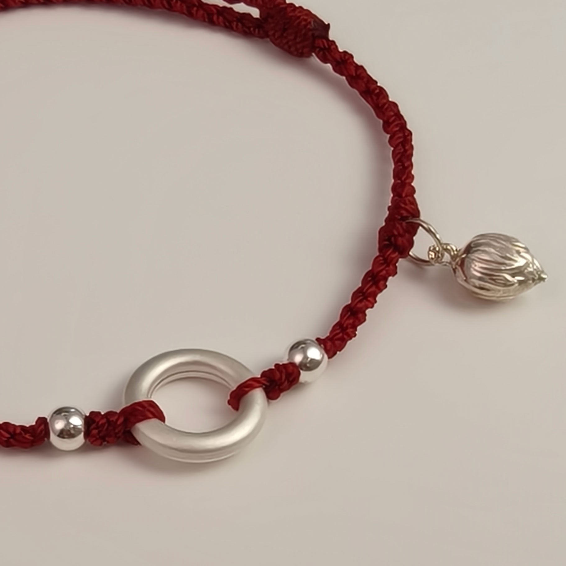 A timeless red string bracelet, woven with silver accents and a lotus charm — a symbol of protection and renewal.